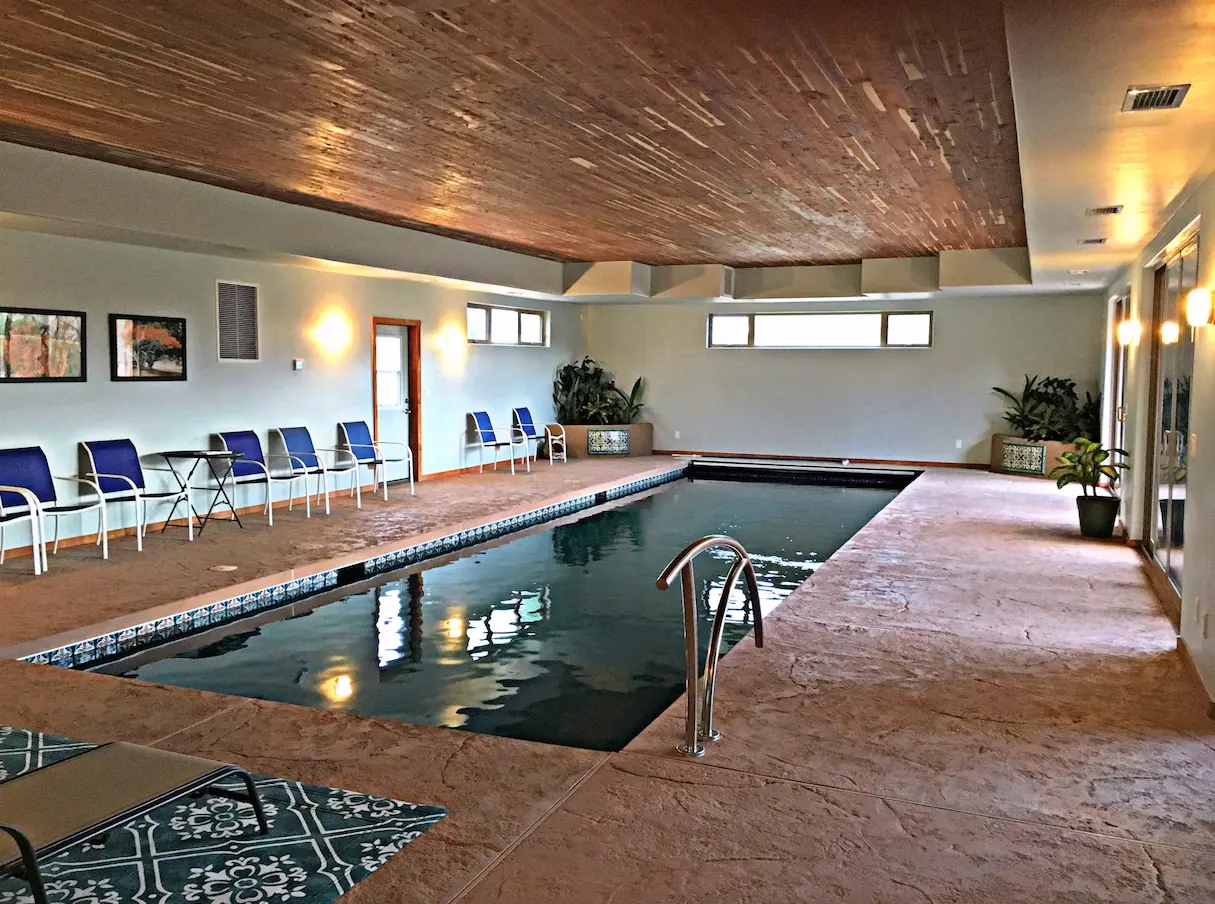 Indoor lap pool with stamped concrete deck and wood ceiling