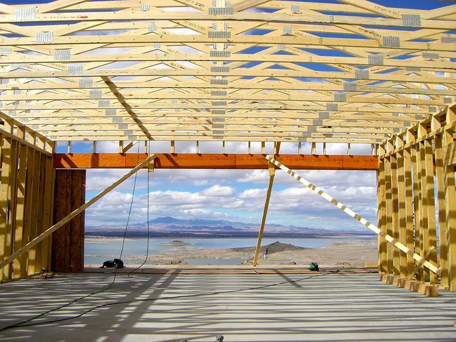 Roof trusses and wall framing opening onto a mountain and lake view