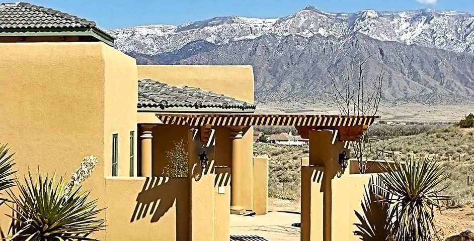 Stucco house with pergola, yucca and snowy mountains behind